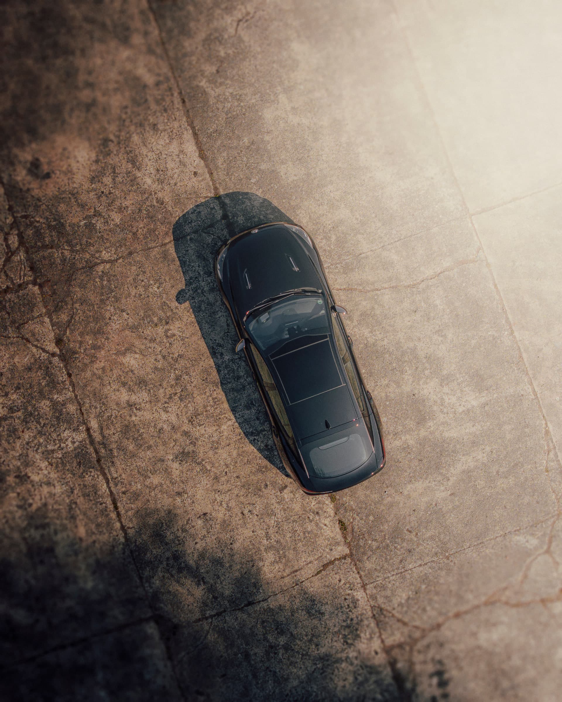 Drohnenaufnahme senkrecht von oben: Kia Stinger auf hellem Asphalt