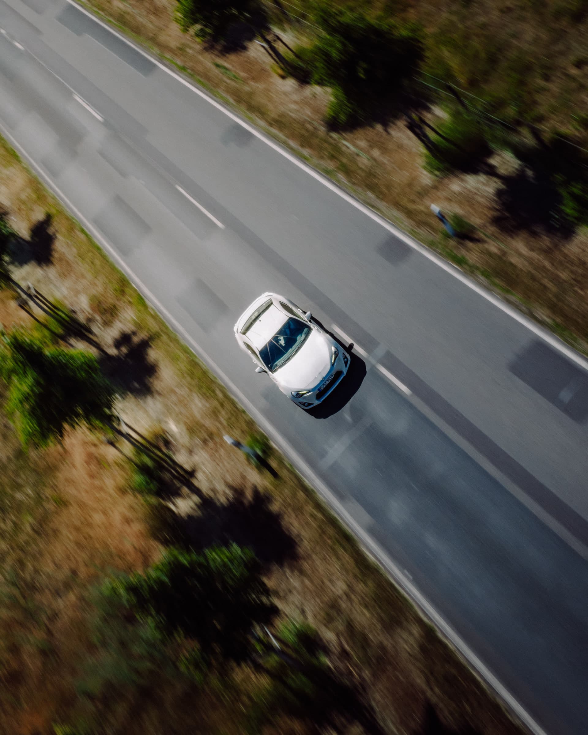 Drohnenaufnahme eines Toyota GT86 auf einer Landstraße von oben