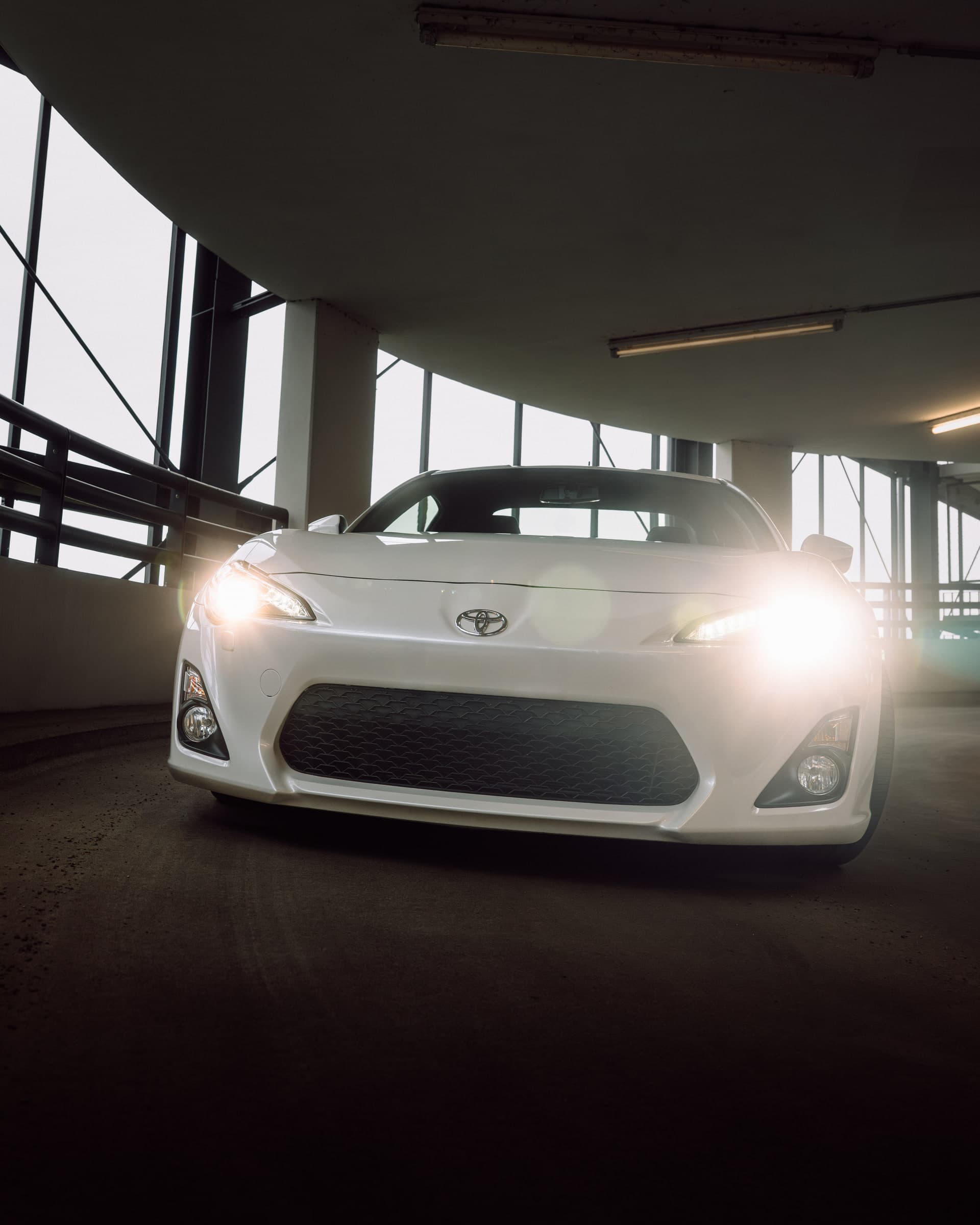 Toyota GT86 mit eingeschalteten Scheinwerfern in einem Parkhaus